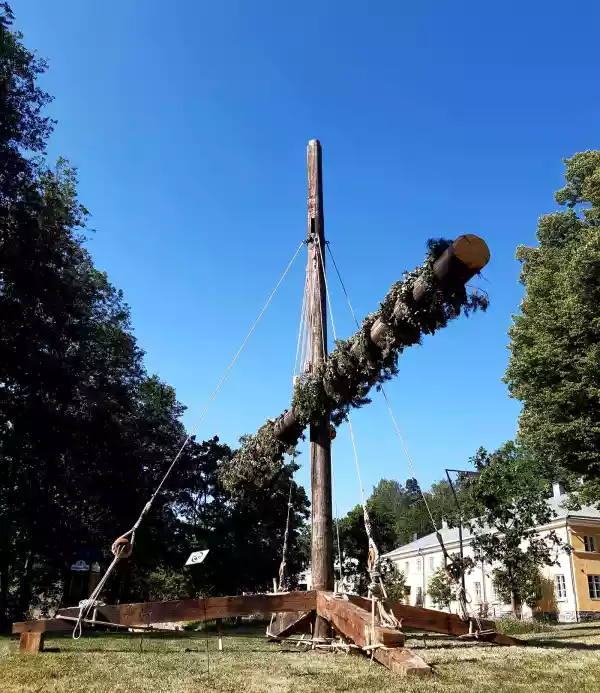 Wooden structure with repurposed ship masts, hoisted and decorated like a maypole and decorated.