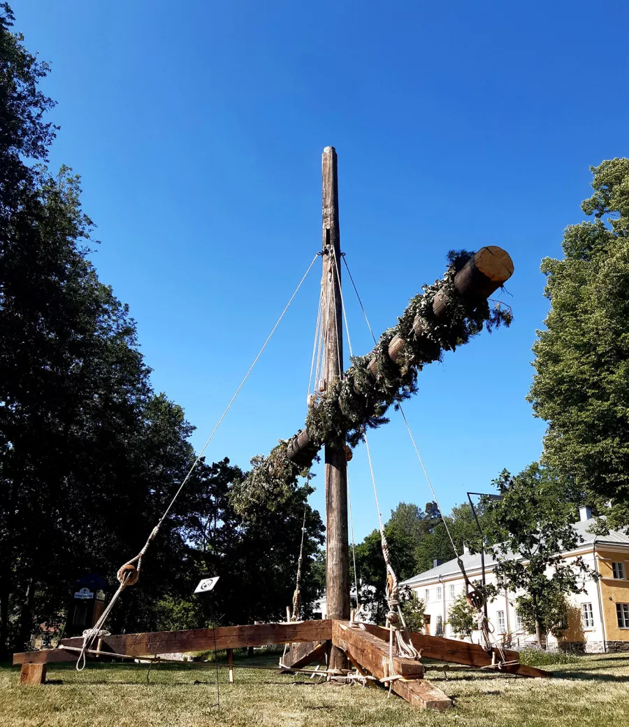 Wooden structure with repurposed ship masts, hoisted and decorated like a maypole and decorated.