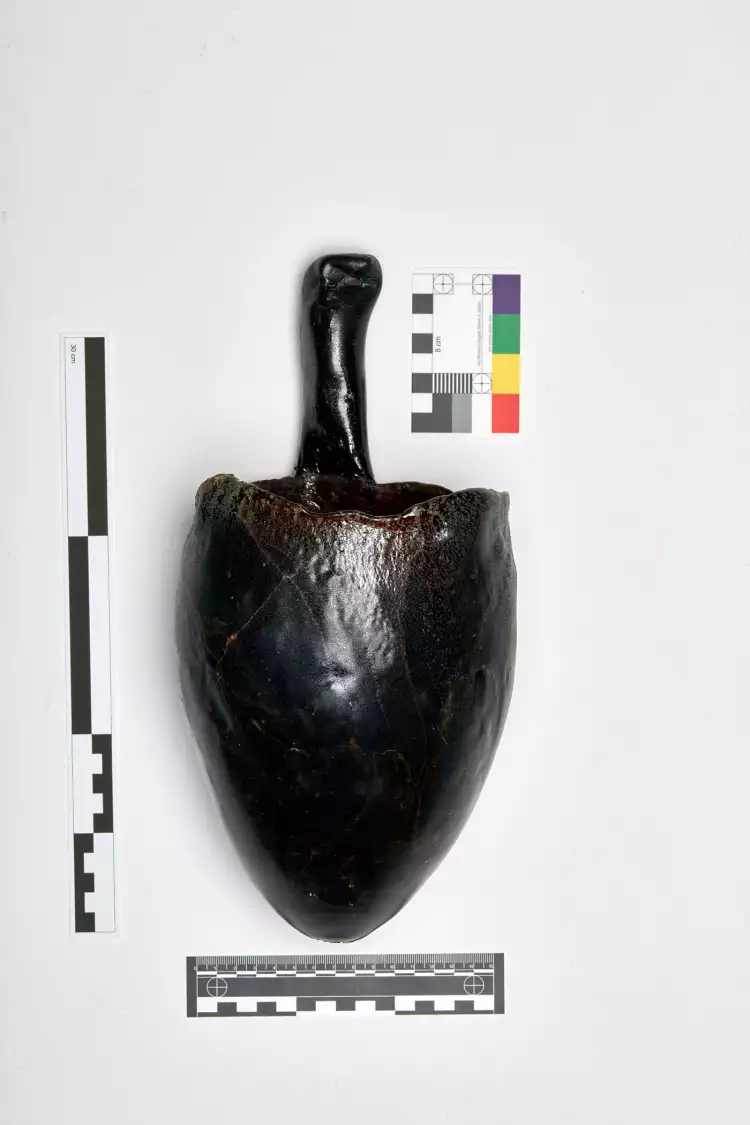 Glass piece shown with several archaeological measuring tools.